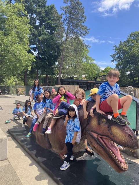 Group of kids sitting on a plastic dinosaur